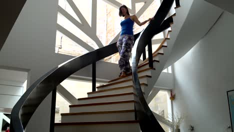 a woman descends the stairs from the top floor of the house