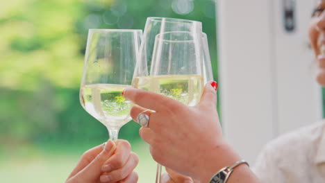 Close-Up-Of-Female-Friends-Relaxing-At-Home-Sitting-In-Lounge-Celebrating-With-Glass-Of-Wine