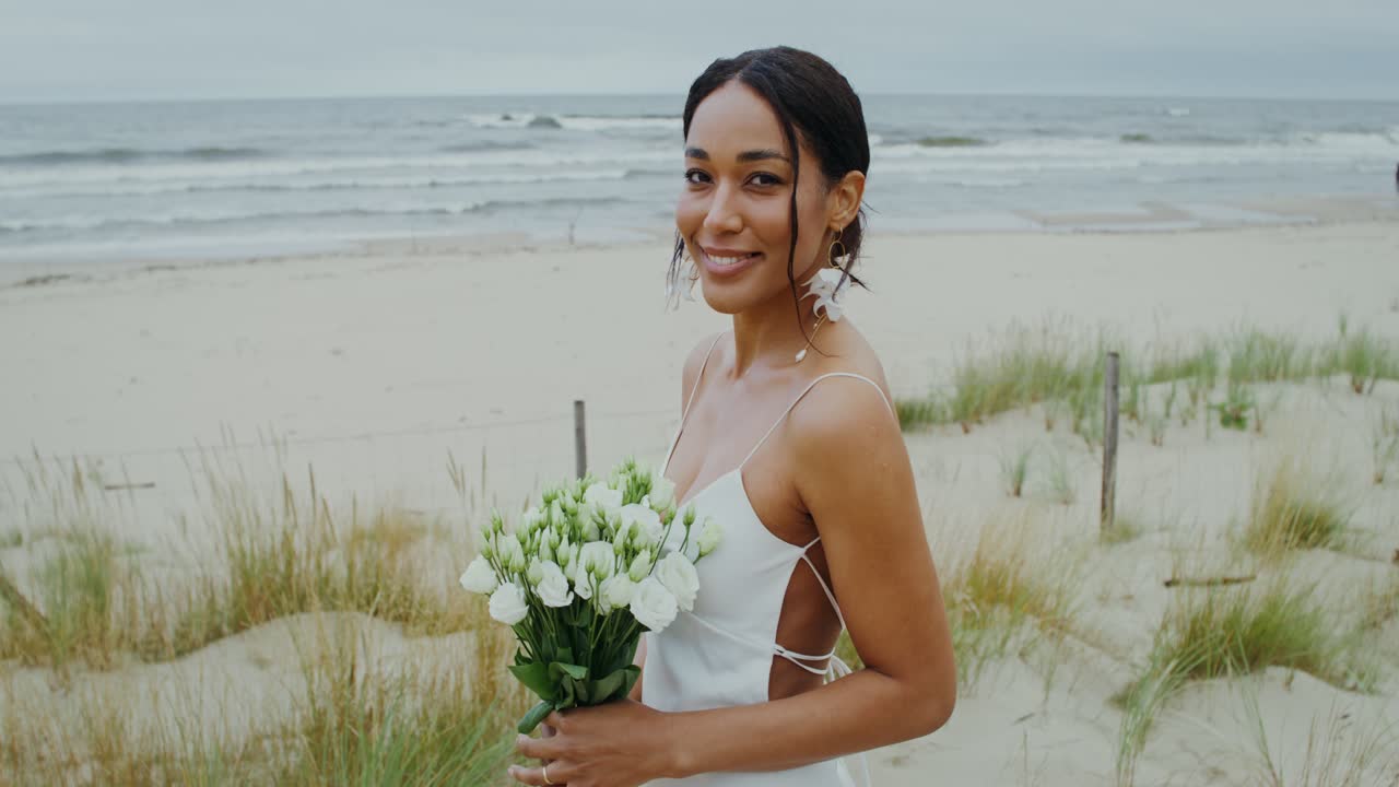 Una sposa su una spiaggia con un bouquet