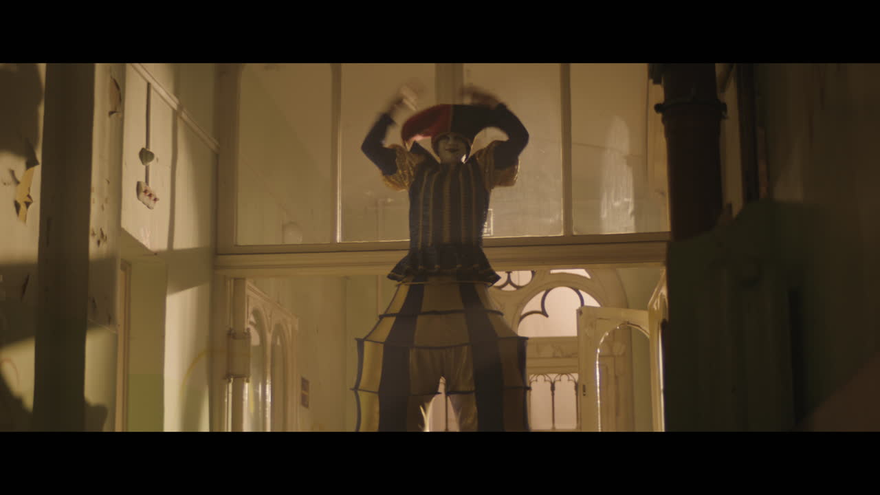 A girl and strange clown on stilts in a dark corridor at night