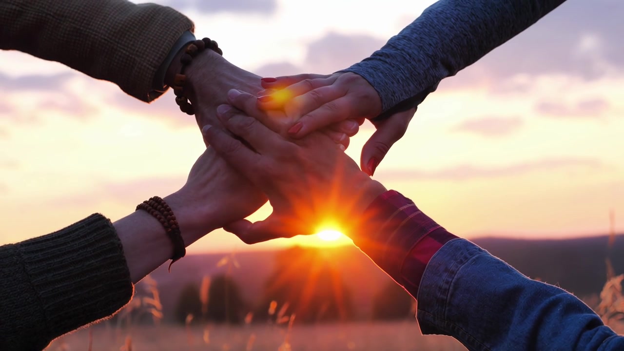 Team Stacking Hands Together at Sunset