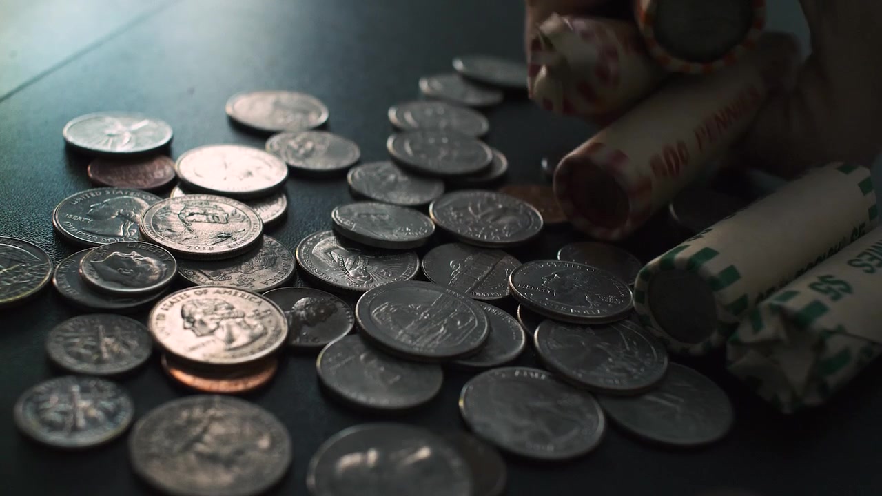 Toczące się monety w zwolnionym tempie, ręka sięga, aby złapać toczące się monety