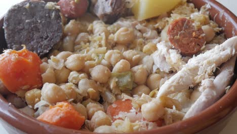 hearty cocido stew with chickpeas, meat, and vegetables in a bowl
