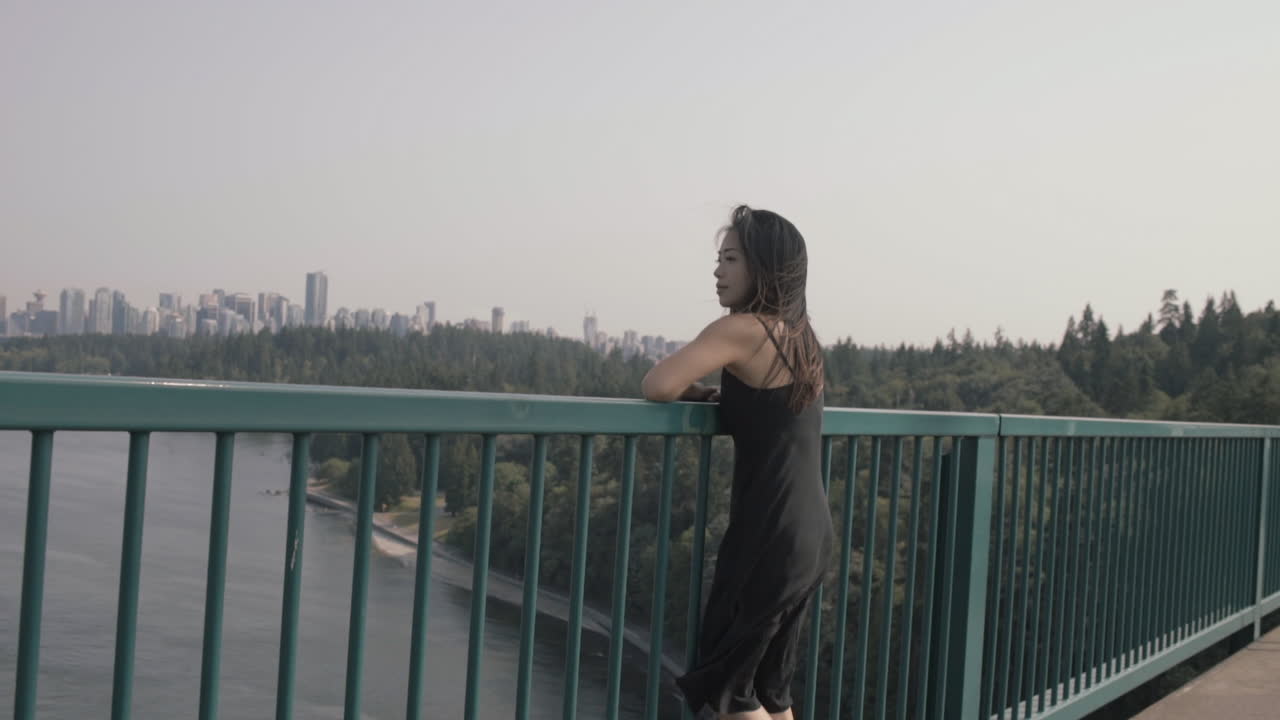 Wide shot of asian woman enjoying view of downtown Vancouver from Lions gate bridge, Slowmo