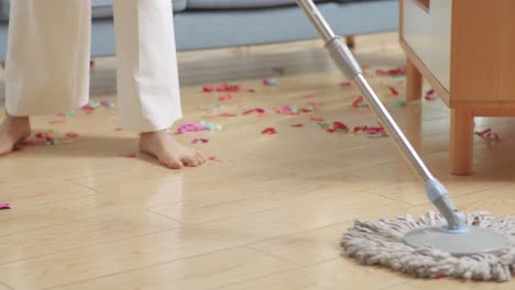 woman cleaning up confetti from wooden floor