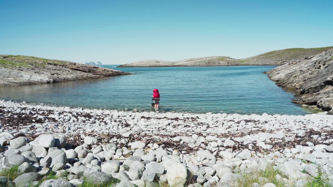 노르웨이 로번드에서 화창한 날 바위투성이의 해변으로 걸어가는 말라뮤트 개를 안고 있는 백패커