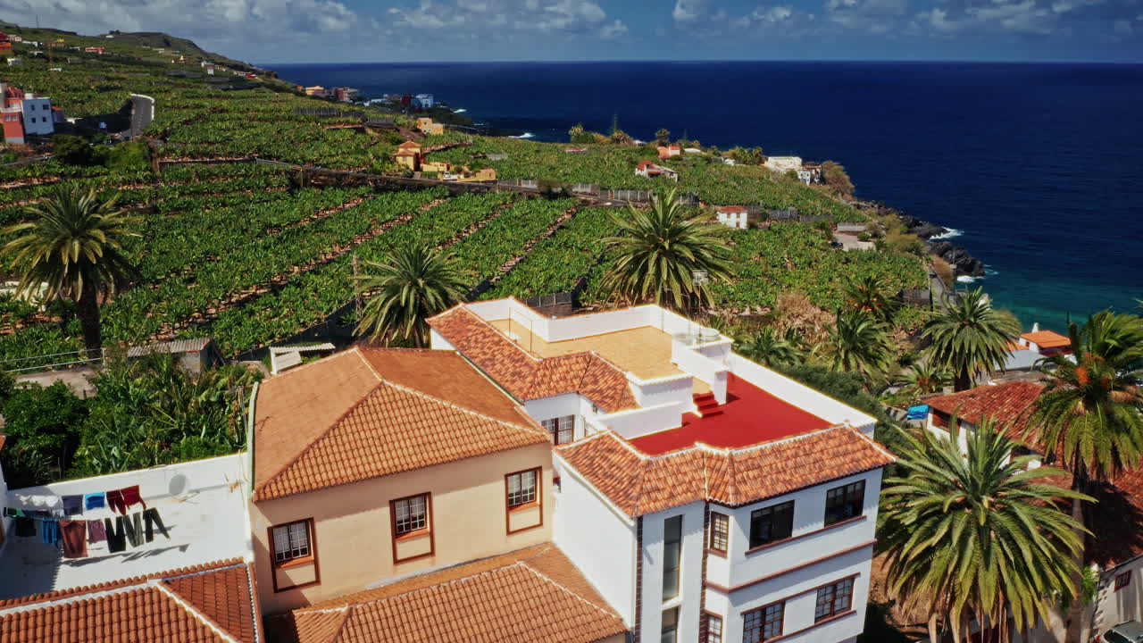 스페인 카나리아 제도 라팔마의 해안선 위에서 찍은 공중 드론. 칠색 바다의 높은 전망, 거친 해안선, 바나나 농장 및 작은 지역 도시. 여름 휴가 목적지.