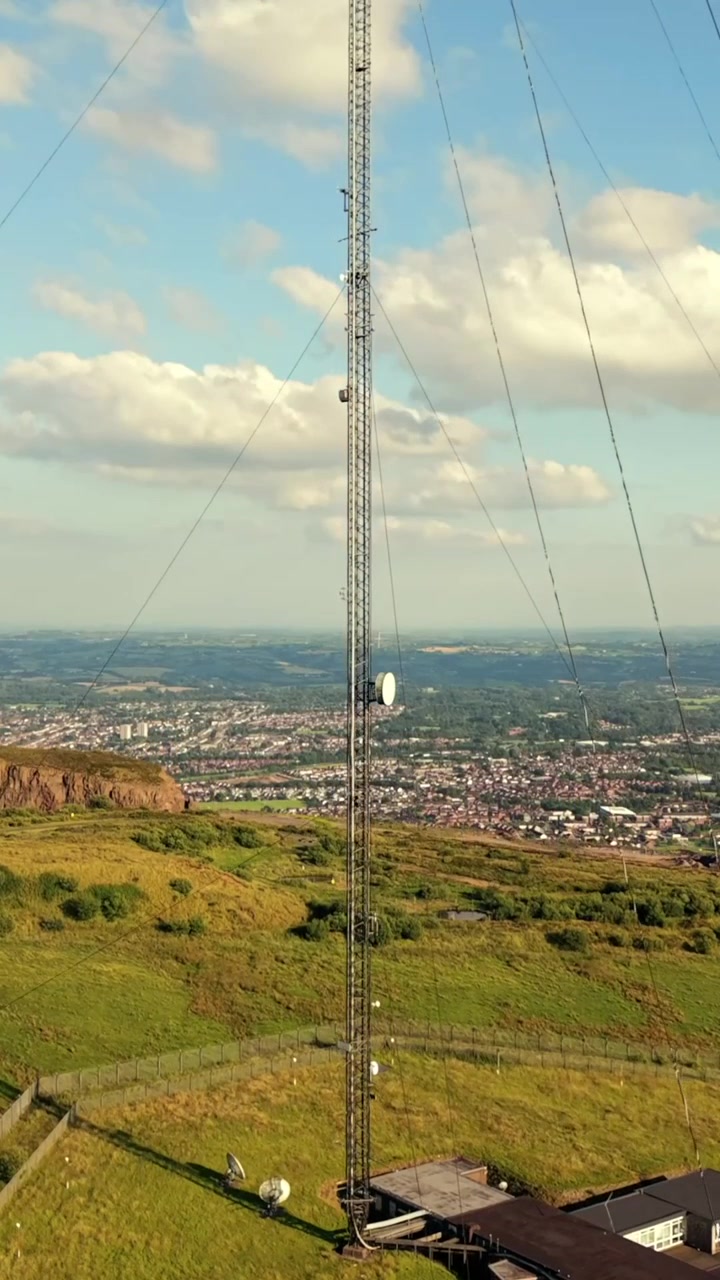Video aéreo ascendente de la Torre Transmisora de Televisión de Black Mountain en Belfast Occidental, Irlanda del Norte, en una luminosa tarde de verano. Producido en 60 FPS, relación social 1080x1920 y con color Rec709