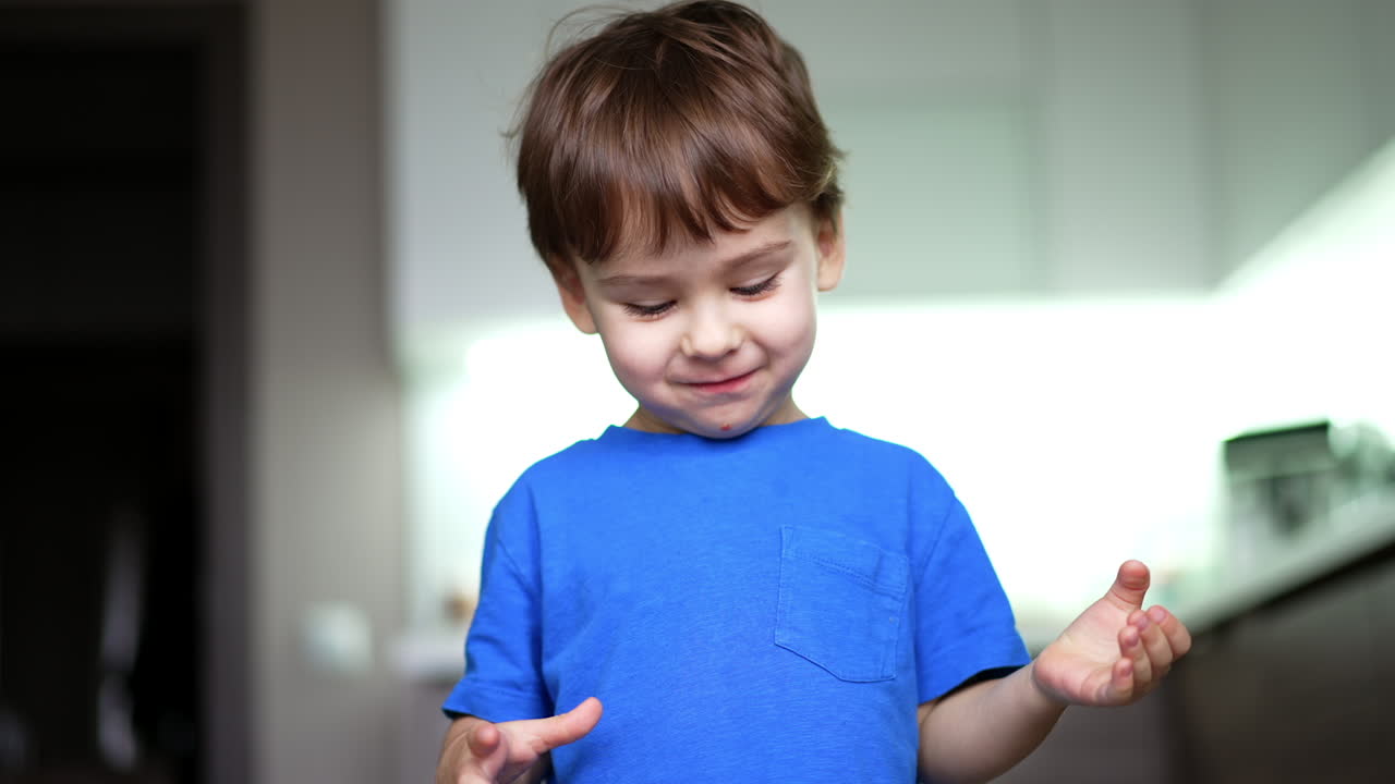 Beautiful smiling baby boy eating an apple. Kid drops the fruit and stands looking at it. Low angle view.