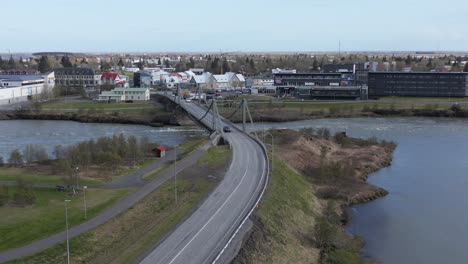 Fliegen-In-Richtung-Kleinstadt-Selfoss-In-Island-Mit-Ölfusárbrú-Brücke-über-Den-Olfusa-Fluss,-Antenne