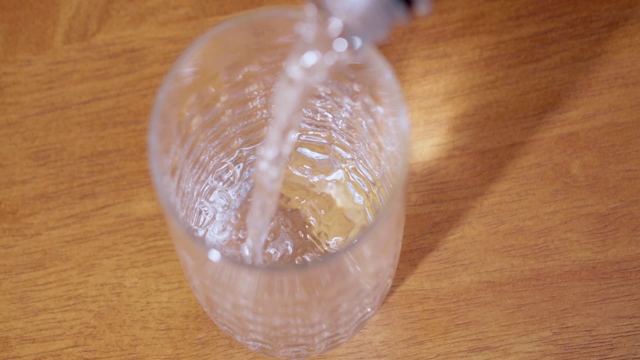 A close-up of water being poured into a clear bottle showcasing refreshment a kitchen setting