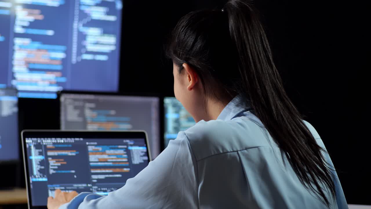 vista de cerca de una programadora asiática escribiendo código en una computadora portátil utilizando múltiples monitores que muestran la base de datos en los escritorios de ventana de terminal en la oficina