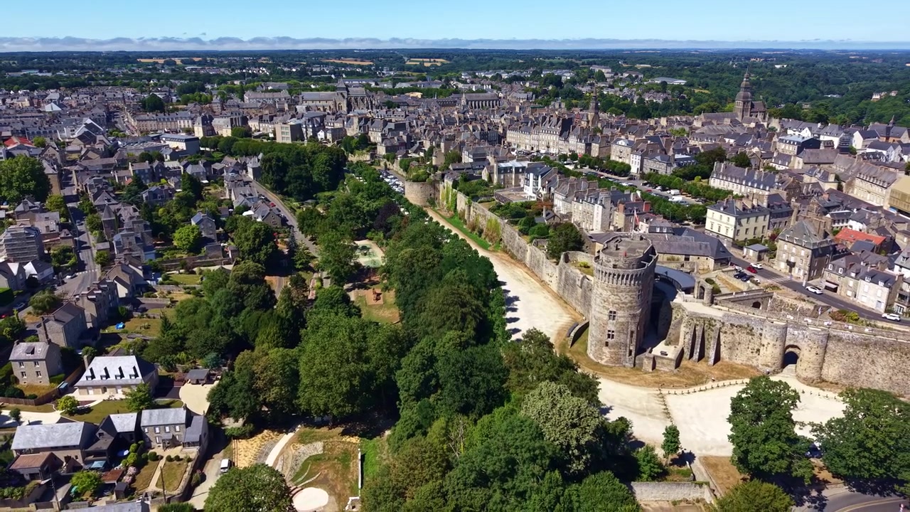 Ripresa aerea con drone che si allontana sopra il Castello di Dinan, rivelando i bastioni medievali, le strade storiche e il centro storico sotto cieli estivi soleggiati