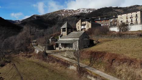 Aerial:-small-chapel-in-the-mountains-with-some-snow-covered-peaks-in-the-background