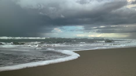 sea waves run along the sandy shore, storm clouds in the background