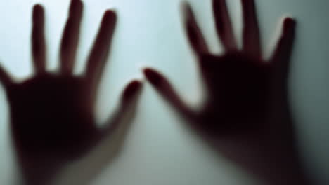 Female-clenching-fists-showing-ten-fingers-behind-frosty-glass.-Macro-video.