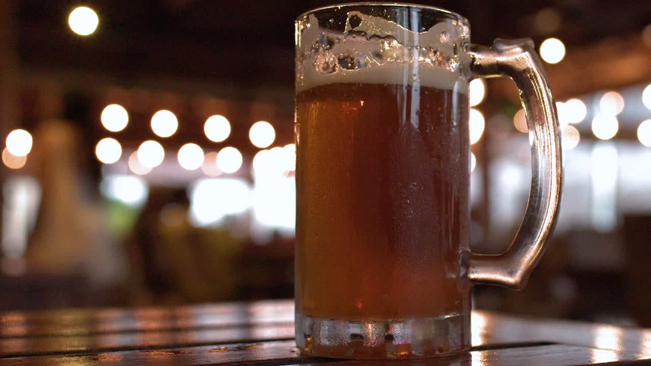 Primo piano di due boccali di birra ghiacciati con condensa su un tavolo di legno di notte.