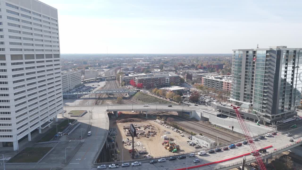 Aerial view of Atlanta featuring large office buildings, high-rise apartments, construction sites, railroads, and busy roads under clear skies.