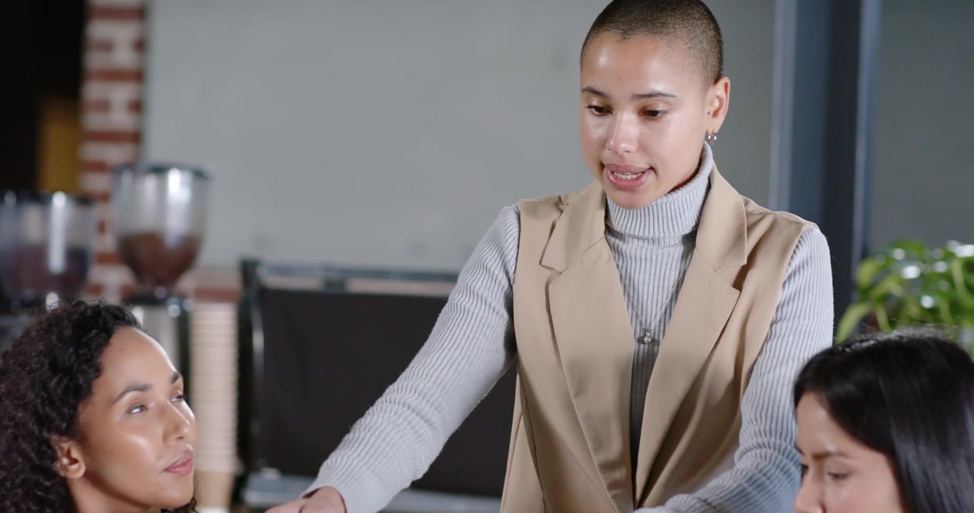 Diverse team with Asian leader leaning in after seeing notes, pointing at office table