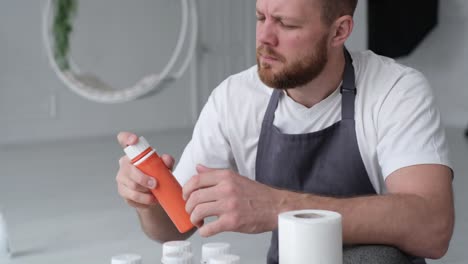 a talented confident focused artist shake and uncorks a tube of orang paint