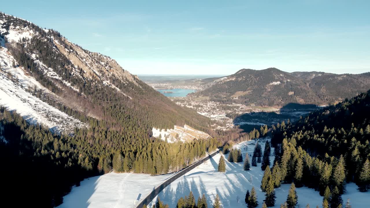impresionante vista aérea desde un avión no tripulado: paso de montaña cubierto de nieve, vista panorámica del schliersee en alemania, paisaje de los alpes bávaros con carretera y lago de montaña lejano en la temporada de invierno