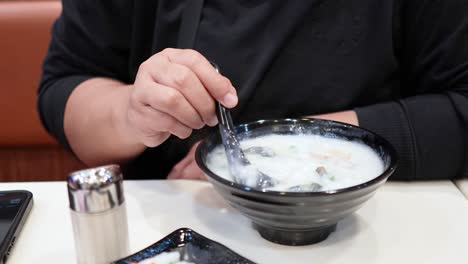 person eating congee with deep-fried dough stick