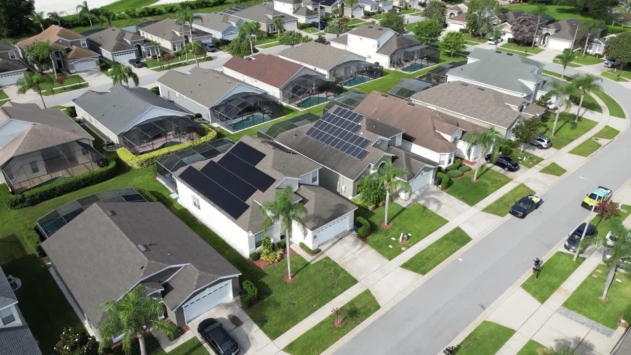 Drone circles a modern house in Kissimmee, Florida, featuring rooftop solar panels and a private backyard pool. Sunny skies and a suburban neighborhood complete this aerial view