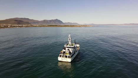 marine research motor vessel operating off the coast with mountains on a calm day