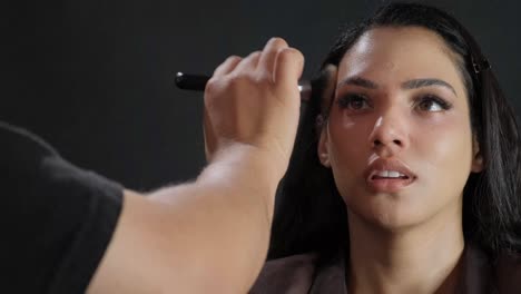 a detailed closeup view of a model receiving a professional makeup application inside a modern studio setting