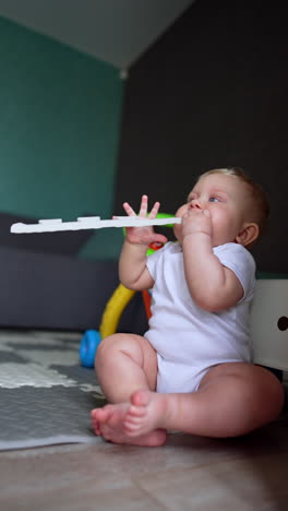 lovely caucasian baby boy takes a toy to his mouth. little infant teething and tries to chew the things around him. vertical video.