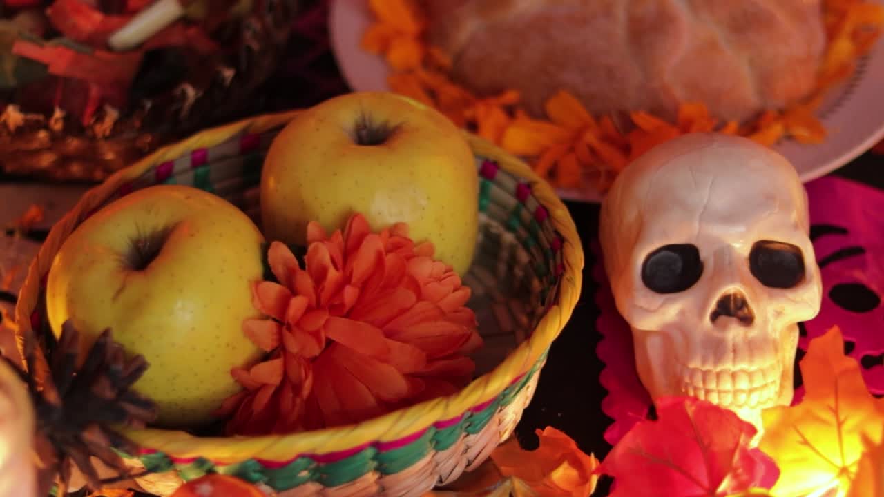 Apple and bread offering and skull decorations on Día de muertos altar