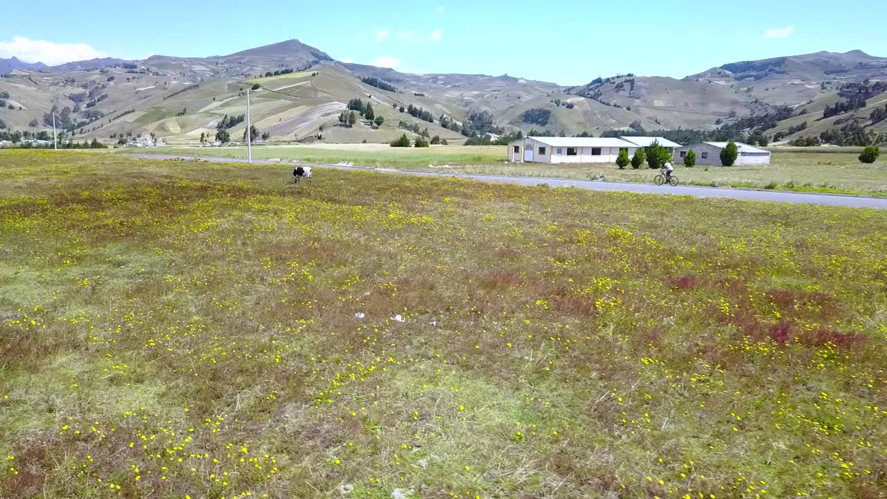 vista aérea de un ciclista montando en bicicleta a lo largo del campo con la cordillera de los andes en quilotoa , ecuador