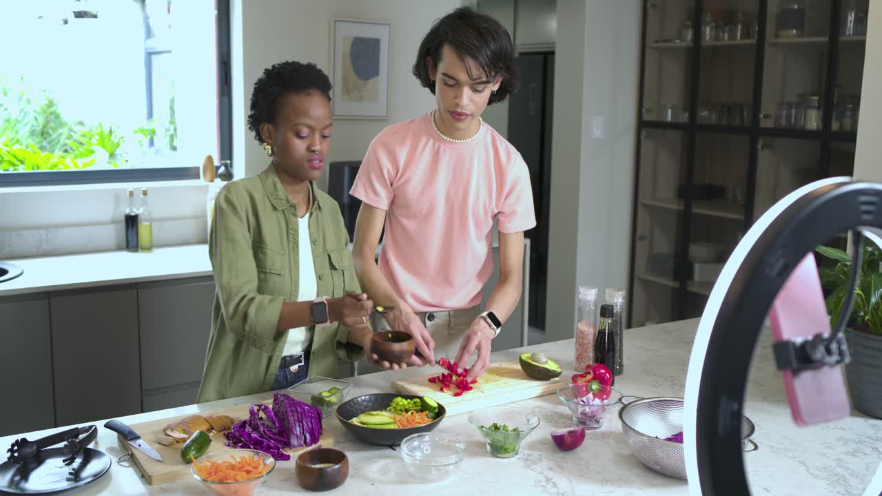 Side om side står forskellige værter og tager edamame og arrangerer peberfrugter i en salatskål i køkkenet