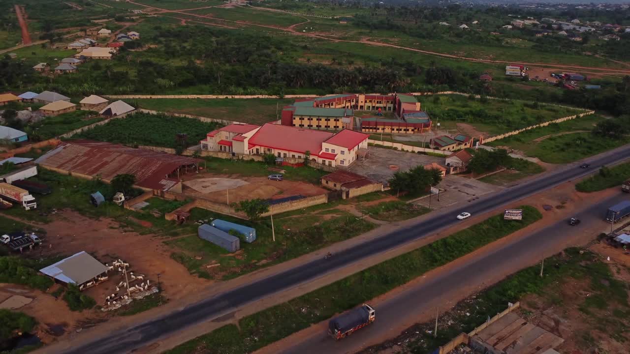 Aerial of compounds and modern buildings alongside a busy road in Nigeria, Africa