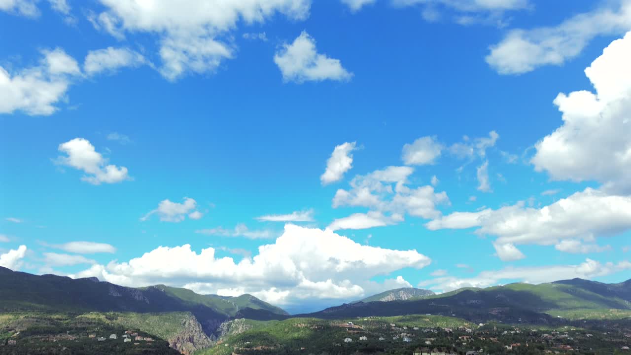 Aerial bird's eye view, push in tilt up revealing beautiful landscape, flying over historical center of Kalamata, ancient castle on the foreground, blue sky with white cloud formations on background