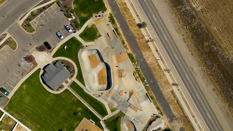 Dizzying aerial spinning view of an urban skate park full of kids having fun in summer