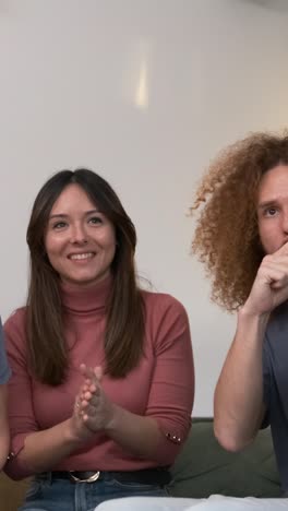diverse friends watching match on couch with drinks and food