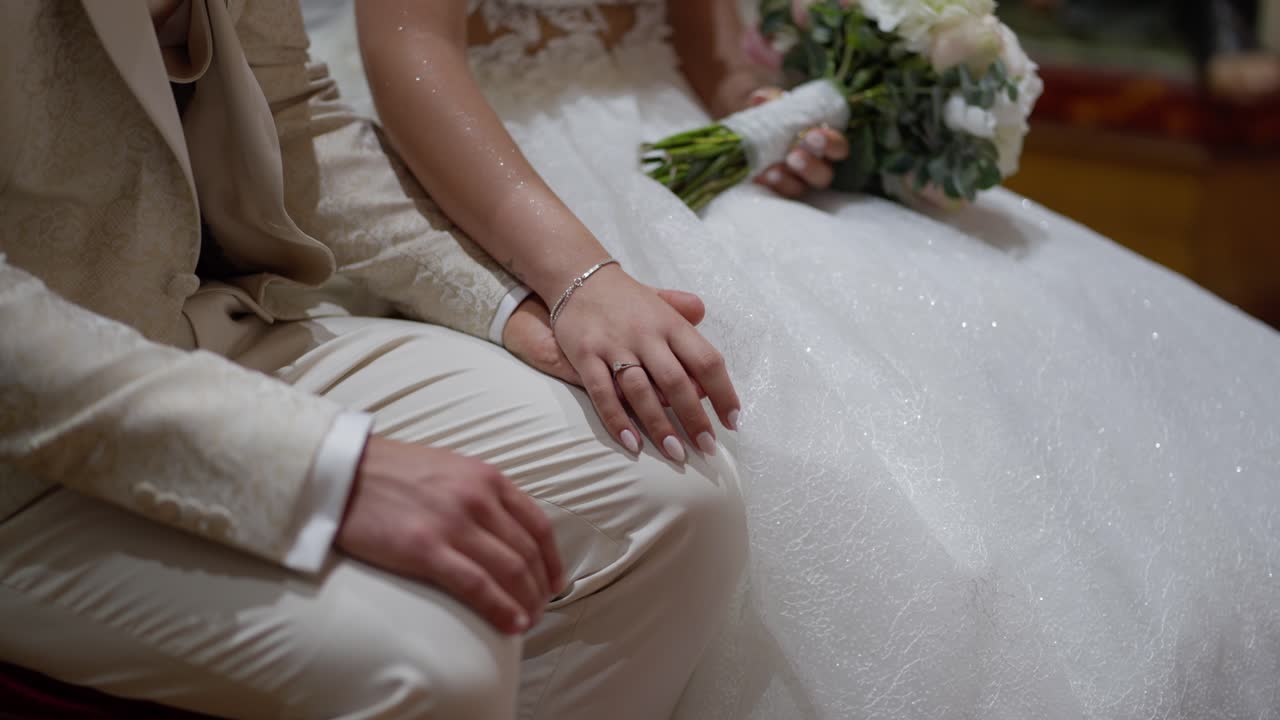 Bride and groom sitting together, hands resting closely, showing unity and love