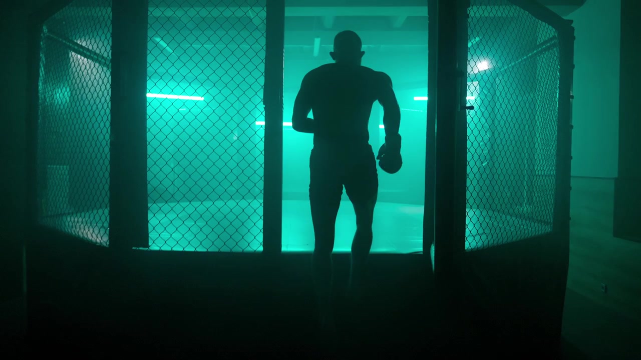 Kæmper går ind i et MMA-bur og skyggebokser i grønt neonlys