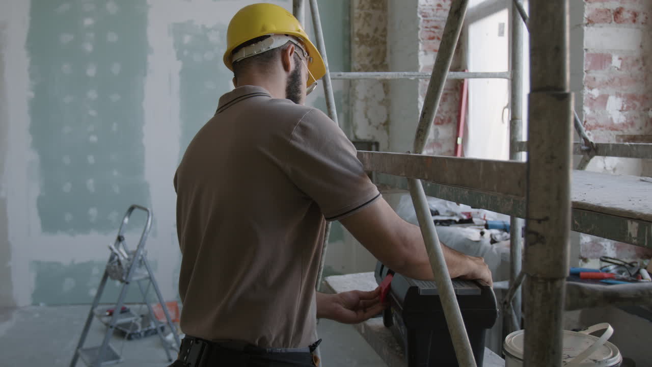 Construction worker on scaffolding with tool box