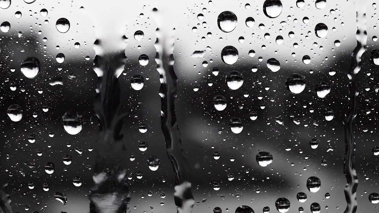 Monochrome water droplets on a glass window pane close up