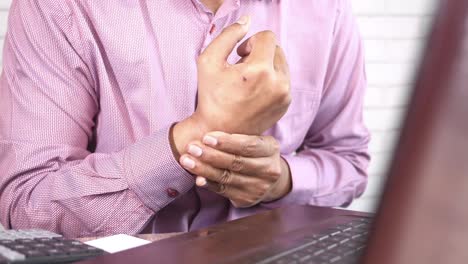 hombre que experimenta dolor en la muñeca en el lugar de trabajo