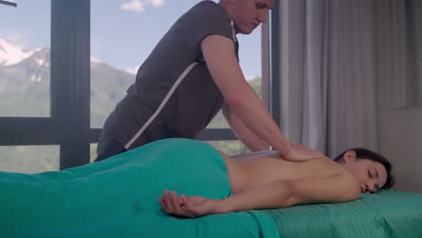 mujer recibiendo masaje de espalda con vistas panorámicas a las montañas