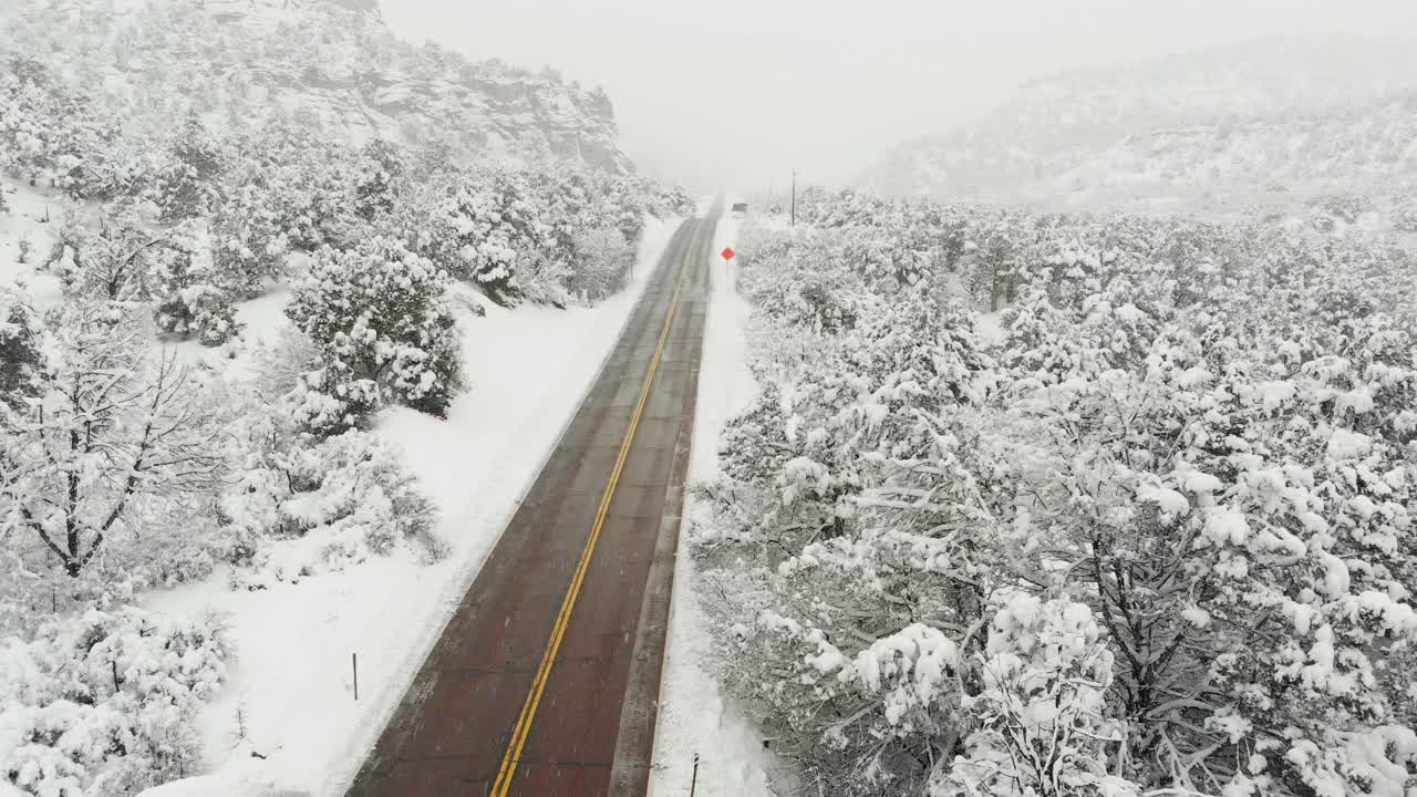 Low flying Aerial shot showcasing the freshly fallen snow blanketing the landscape and icing over the evergreen trees in Zion national park