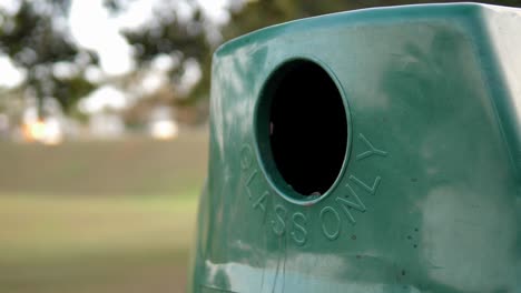 Caucasian-right-hand-places-green-glass-bottle-in-sorted-recycle-bin,-close-up