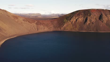 aerial: blahylur crater lake has placid, crystal-clear waters surrounded by mountains