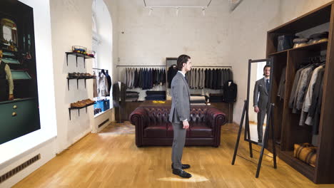 Young-man-trying-on-suit-in-front-of-mirror-in-classy-boutique-shop