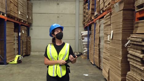 una empleada, caminando por el área de almacenamiento de un almacén, inspeccionando los estantes y tocando un panel táctil