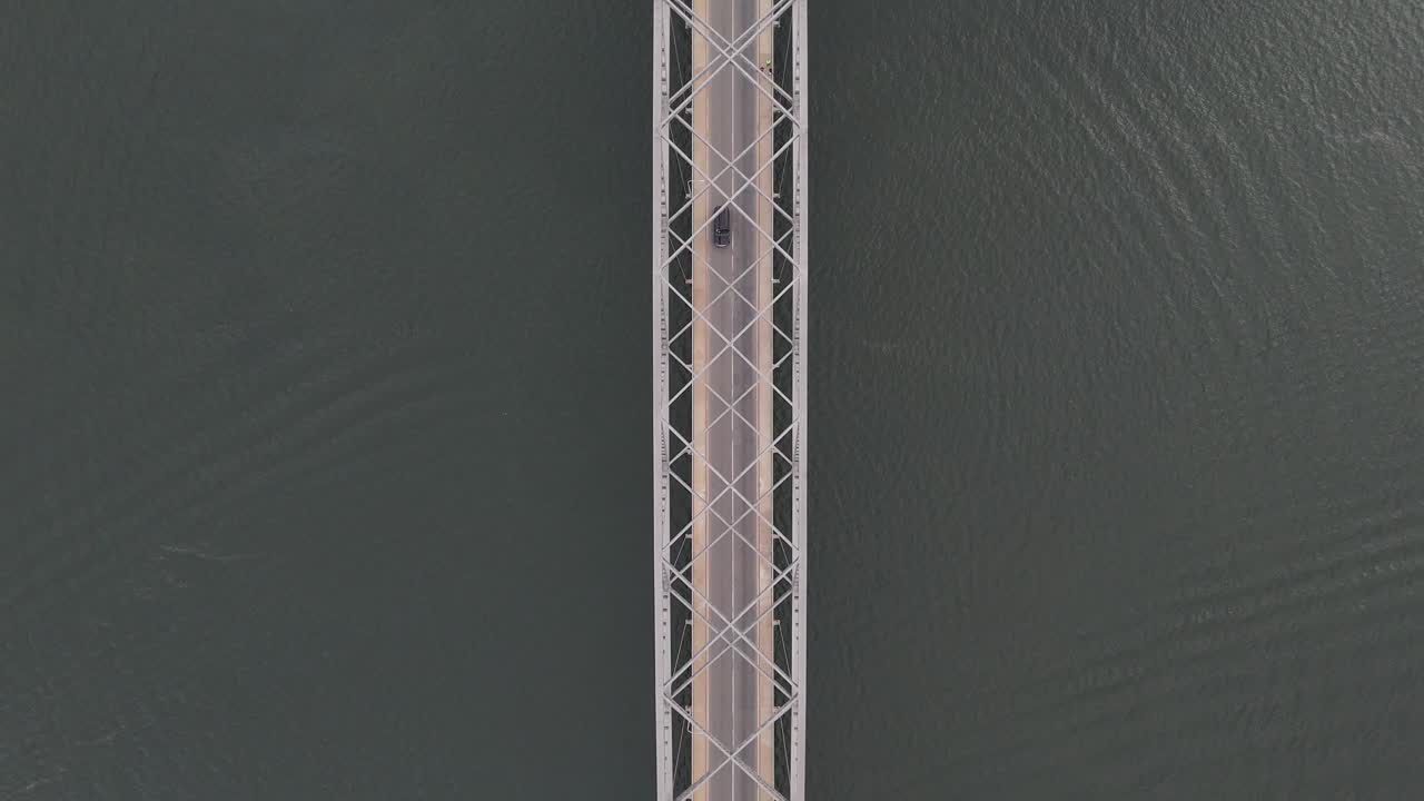 Ripresa cinematica zenitale con drone di un'auto che attraversa il Ponte Adomi sul fiume Volta ad Akosombo, Ghana. Infrastruttura dell'Africa occidentale e paesaggio fluviale.