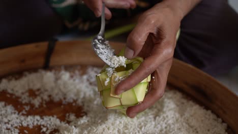 the process of putting rice in the ketupat, before cooking